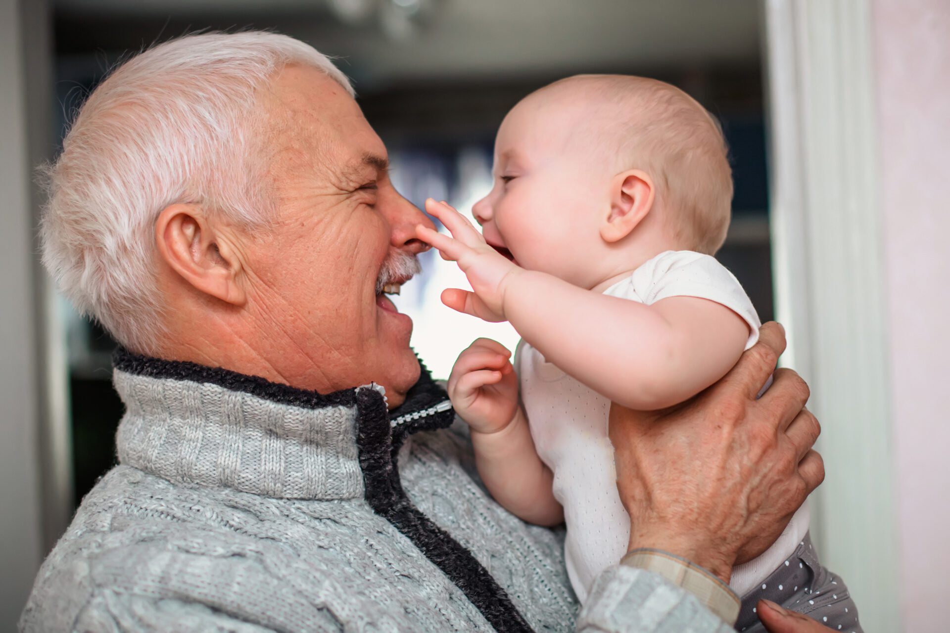 A newborn baby touches the old grandfather by the nose A newborn baby touches the old grandfather by the nose